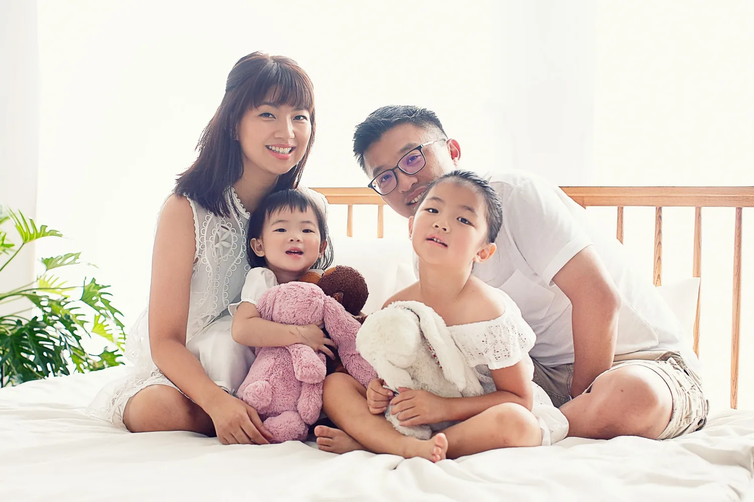 Indoor family portrait with soft window light and two daughters in Singapore