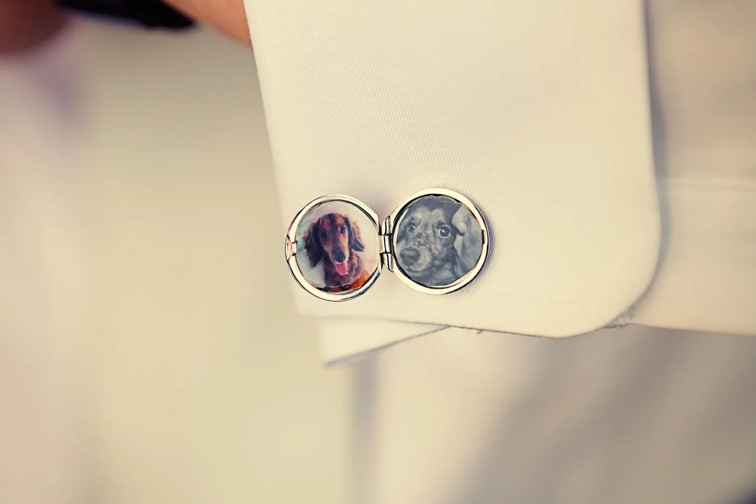 Two circular lockets with dog portraits attached to cream-colored fabric.