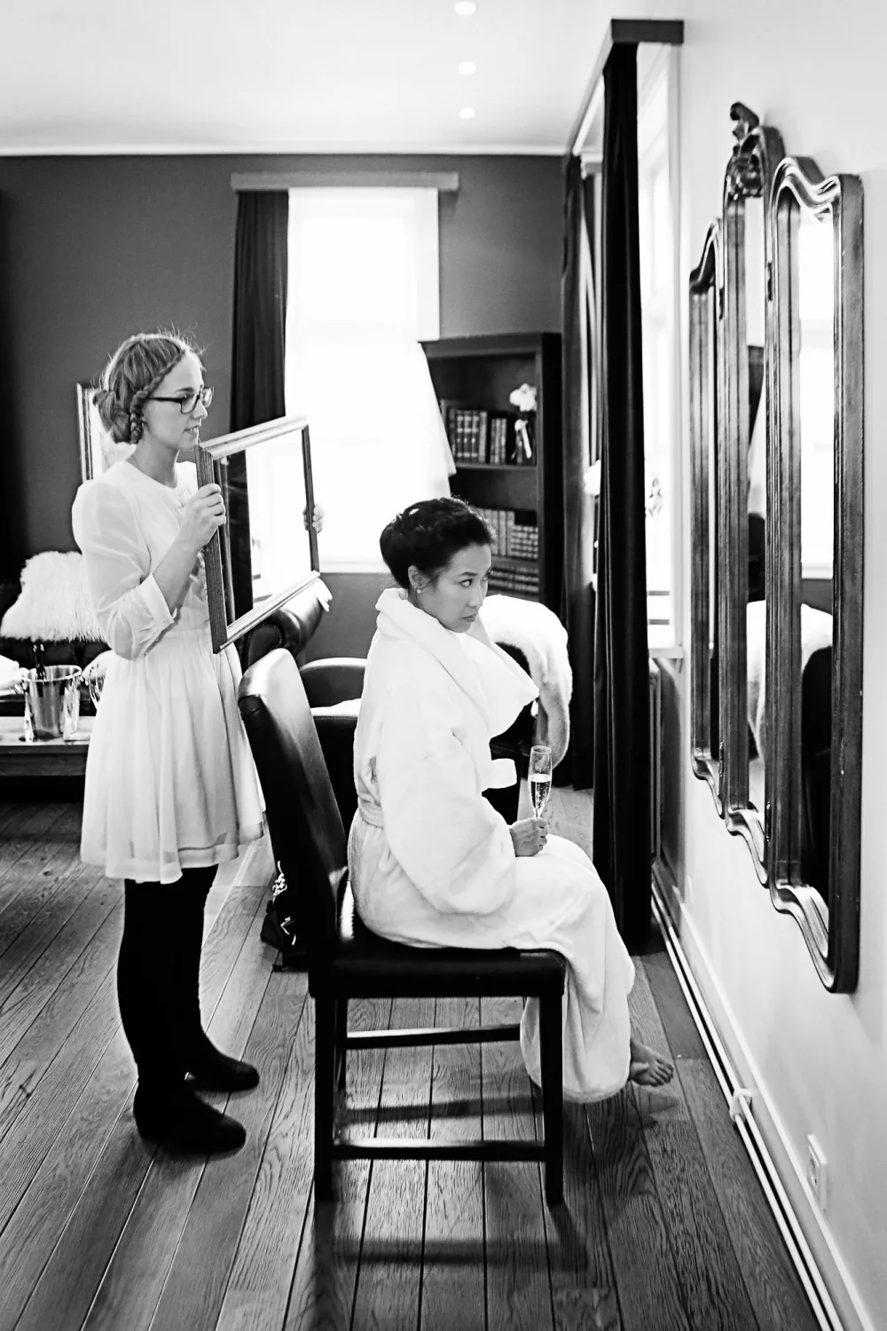 Two people in white clothing in an indoor room with mirrors and modern furnishings.