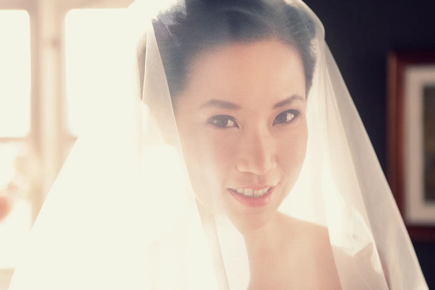 Bride wearing sheer white veil with soft natural lighting from window