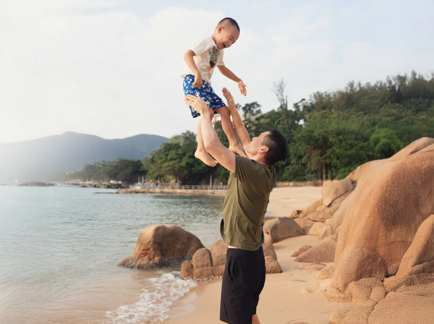Andrew tossing Nathan into the air on the beach