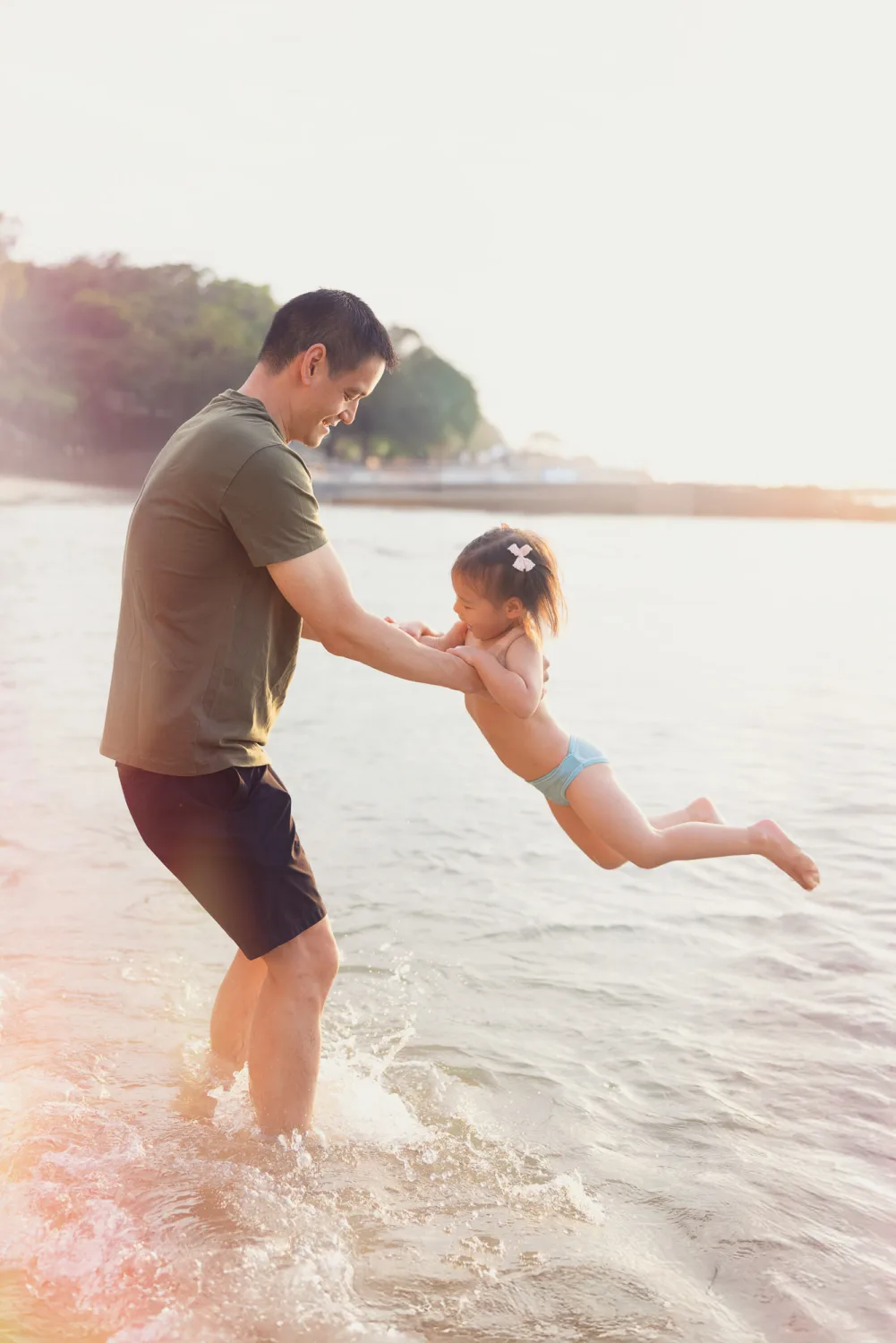 Andrew swinging Amelia above the water at the beach