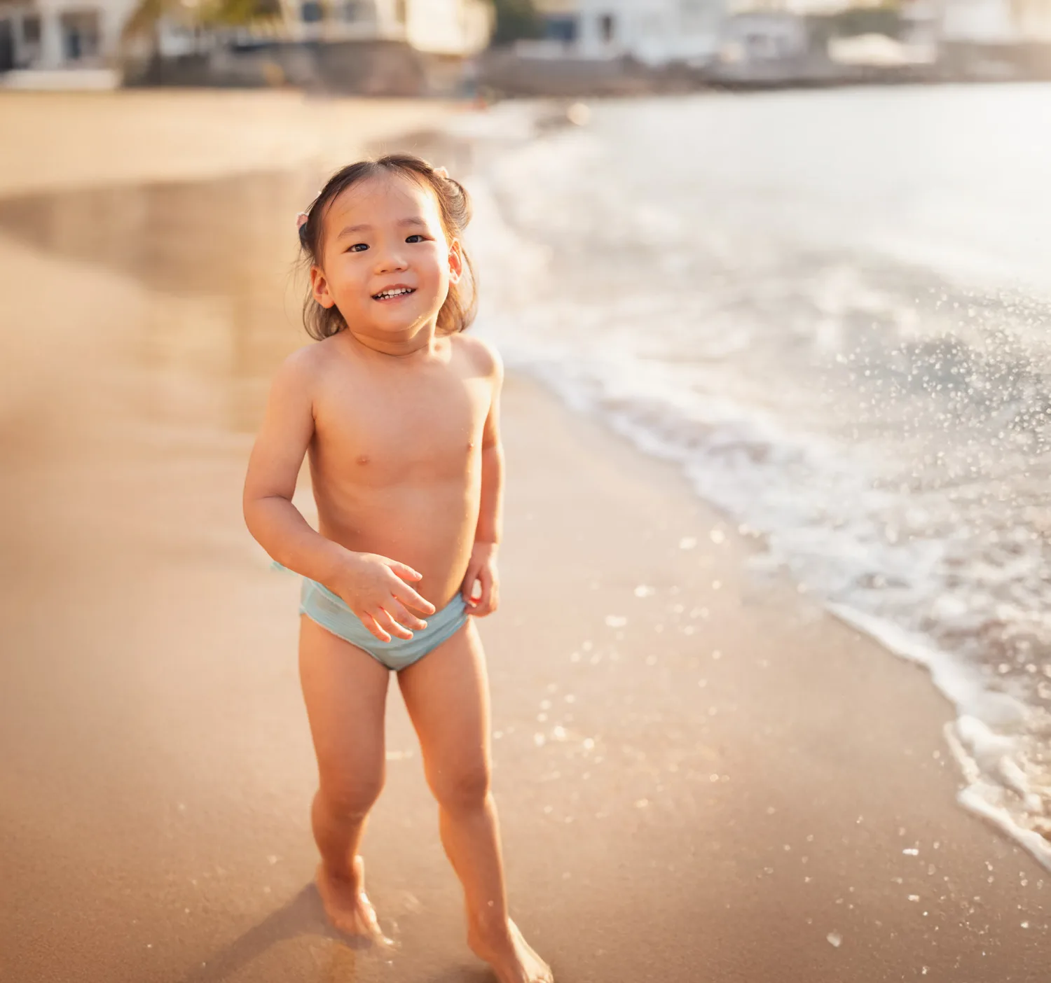Amelia walking through the sand with wet feet at the beach