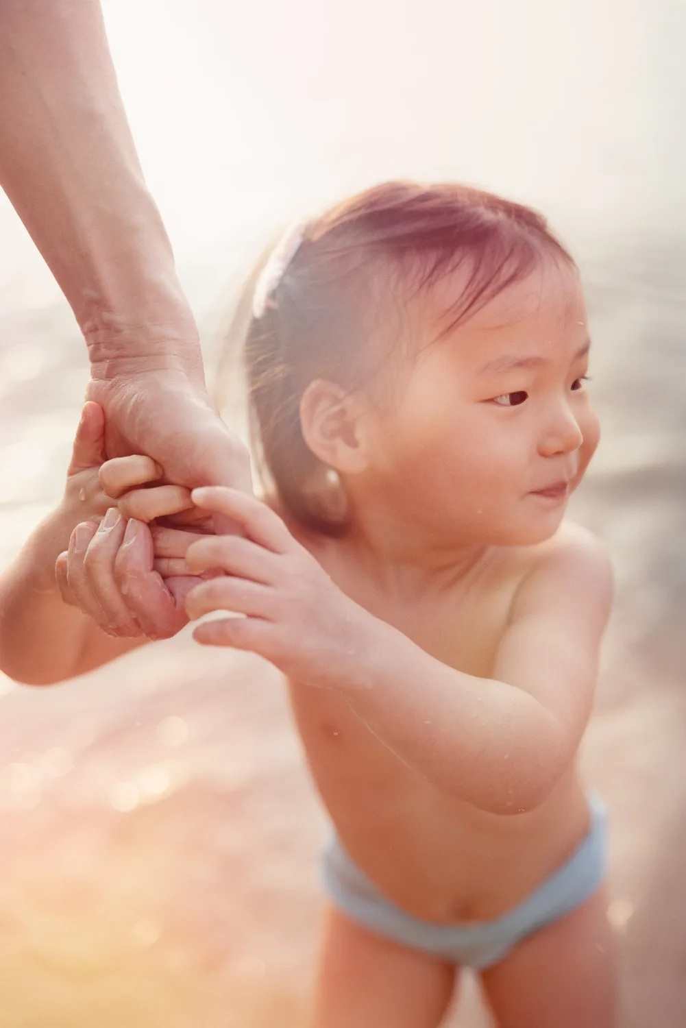 Amelia holding a parent’s hand by the water