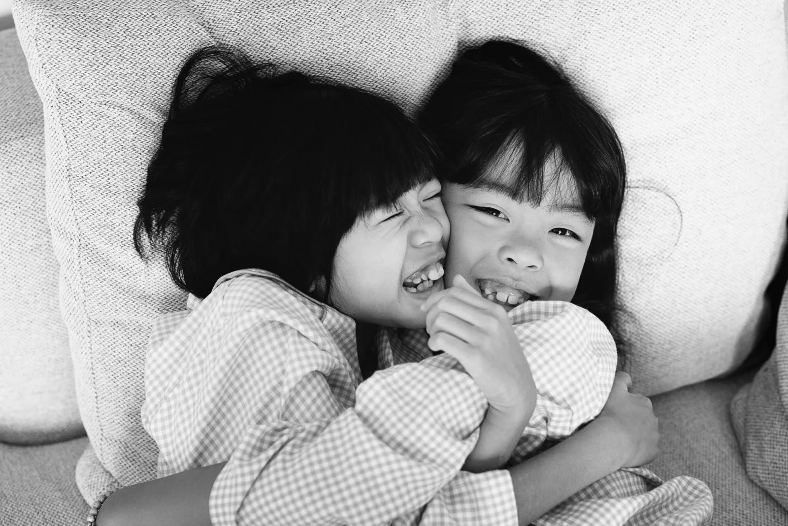 Pillow fight between sisters during creative indoor family shoot in Singapore