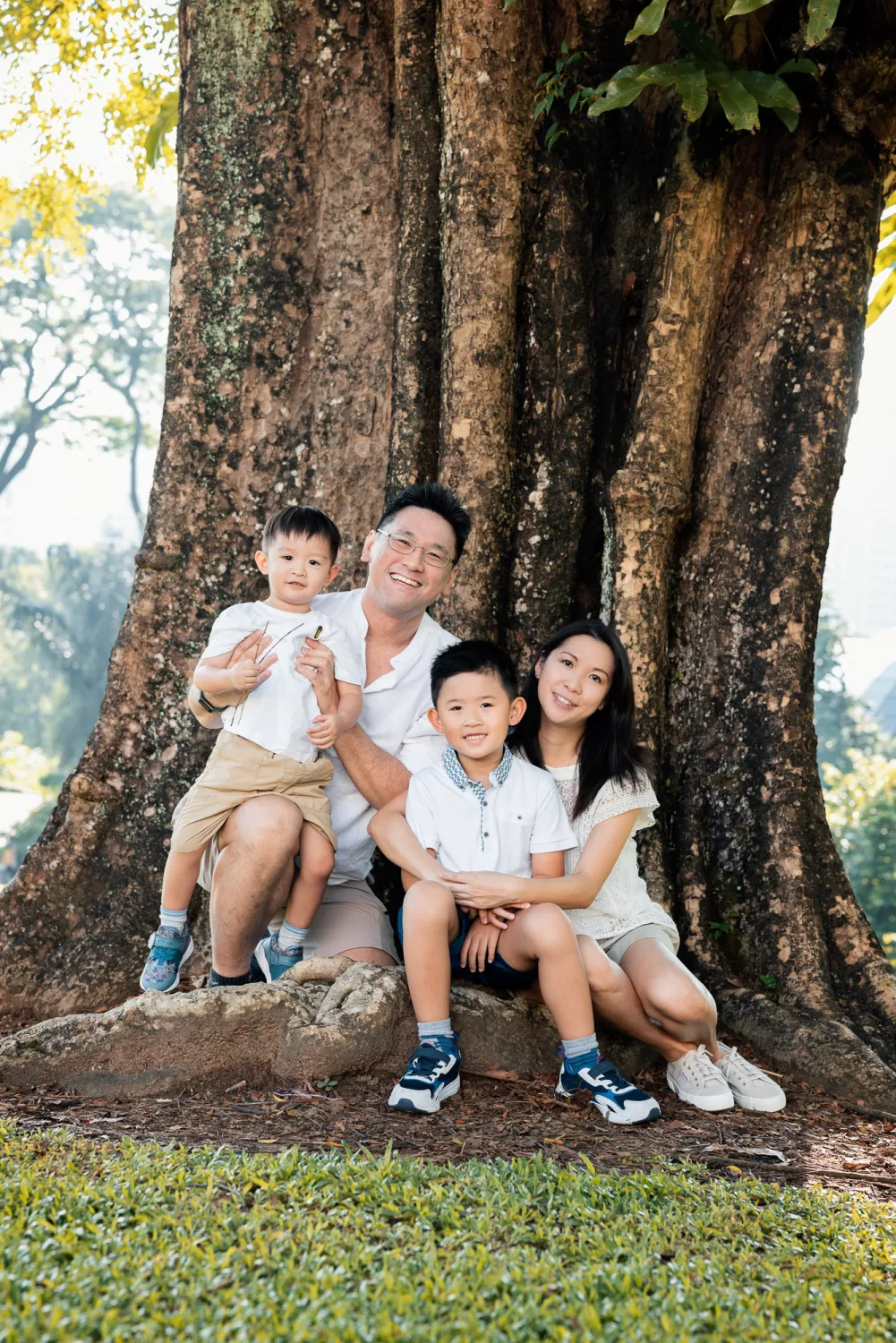 Hilda and Kevin with Tristan and Wesley seated together under the trees at Fort Canning