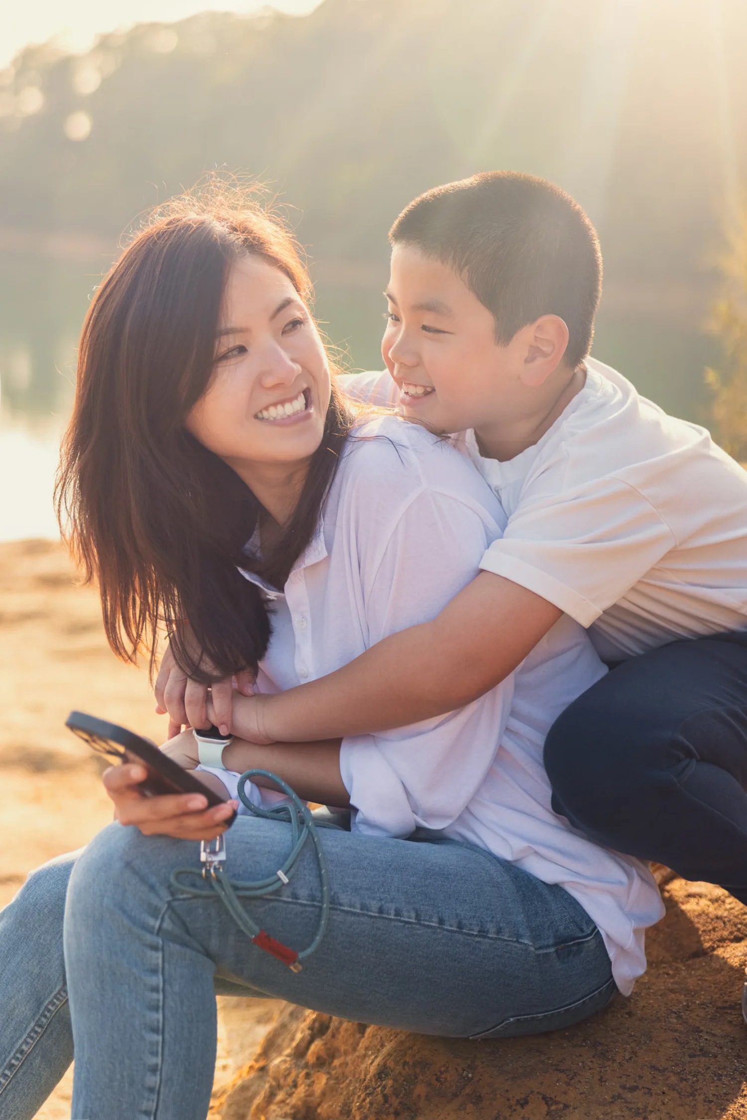 Xenia and Lachlan sharing a joyful embrace by the reservoir during golden hour
