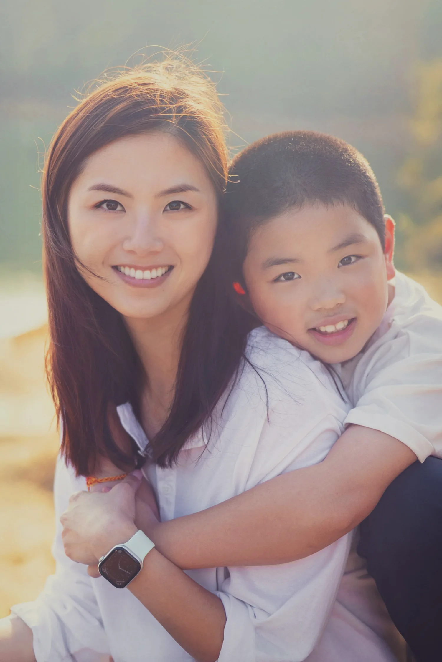 Xenia and Lachlan in a warm golden-hour portrait, son hugging mum as sunlight glows around them