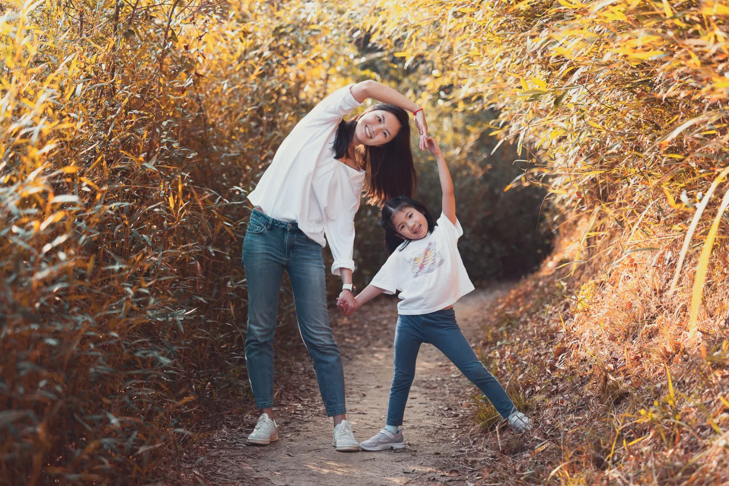 Xenia and Leila making a heart shape with their arms on the golden-lit trail