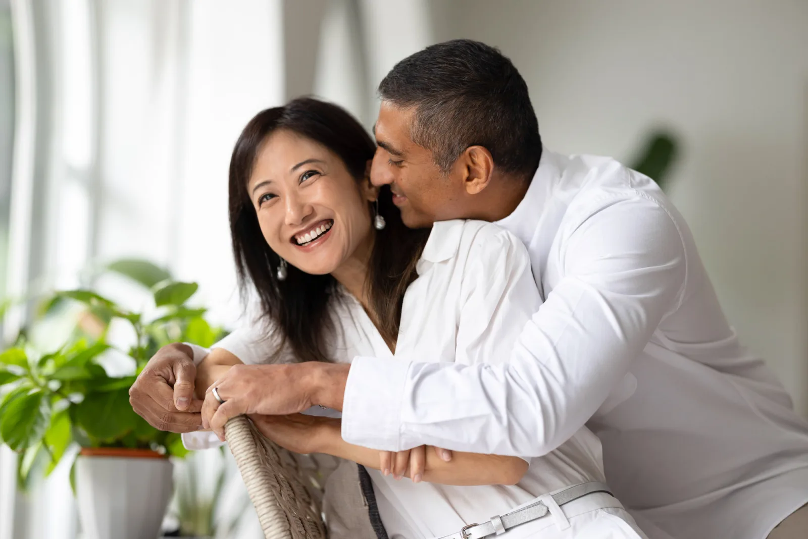 Parents smiling together in their living room with warm natural light during indoor shoot