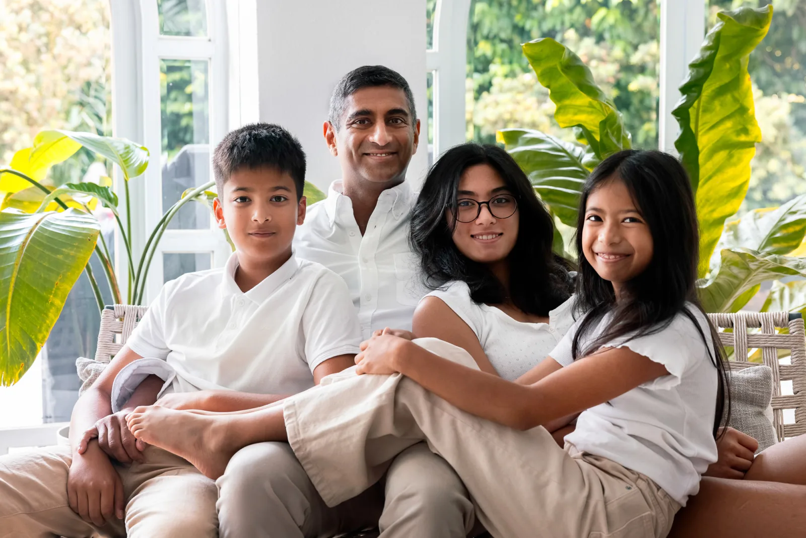 Father and three children sharing a playful moment on the couch