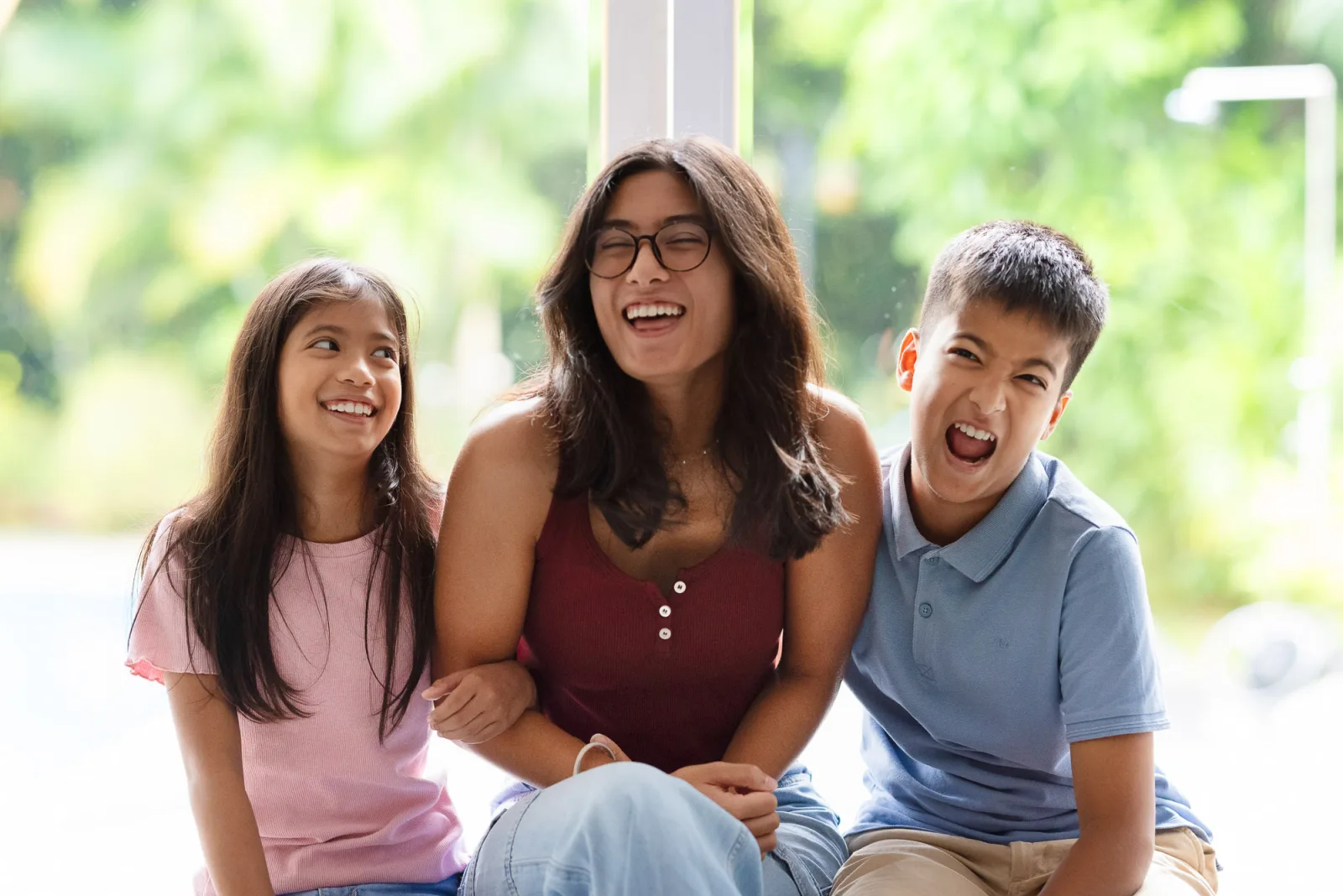 Three siblings sitting together by the window in soft afternoon light