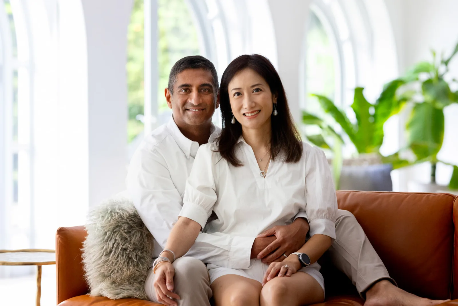 Mother and daughters smiling together in white clothing with natural window light