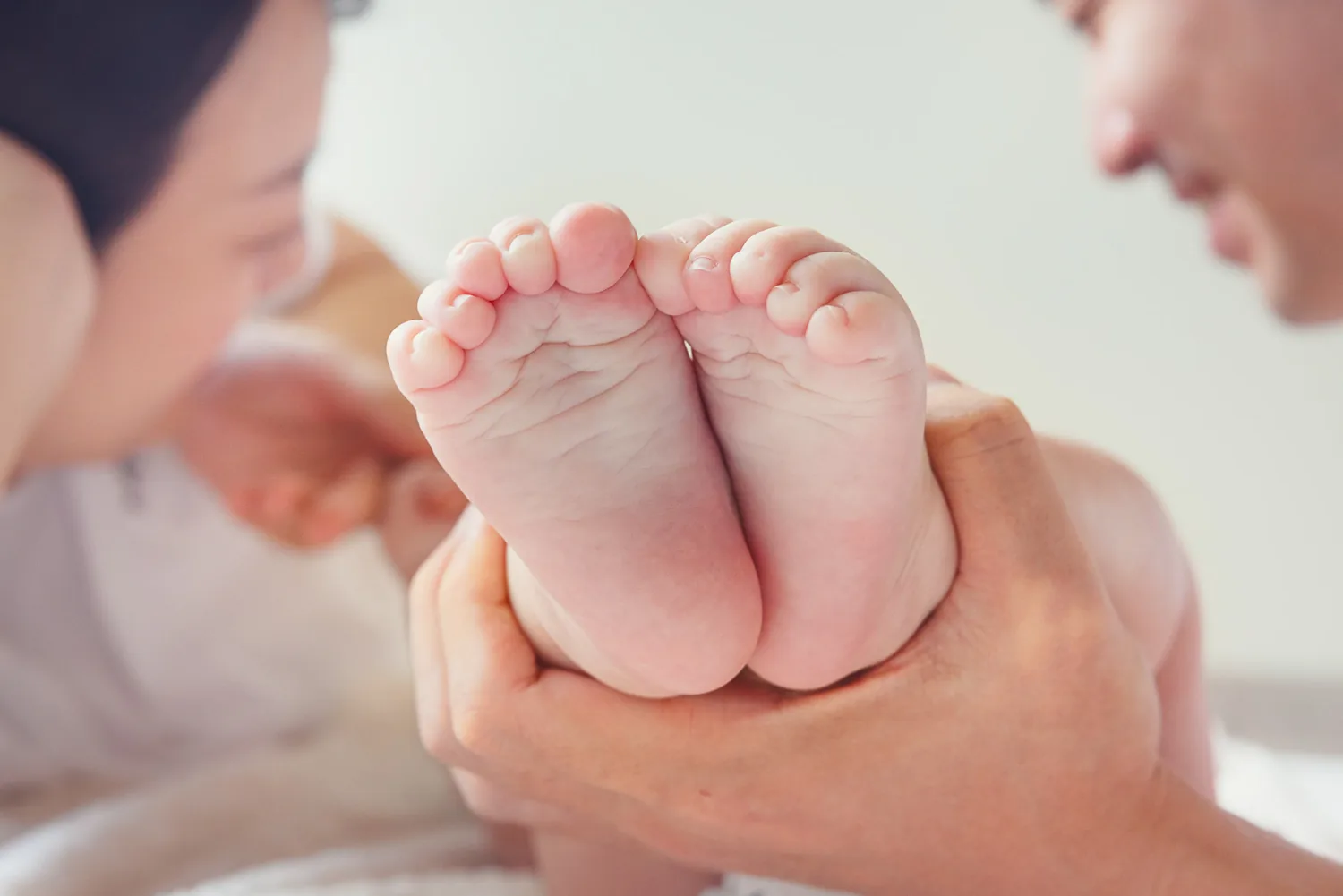 Close-up of Juwon’s feet held in adult hands during the 100-day family session