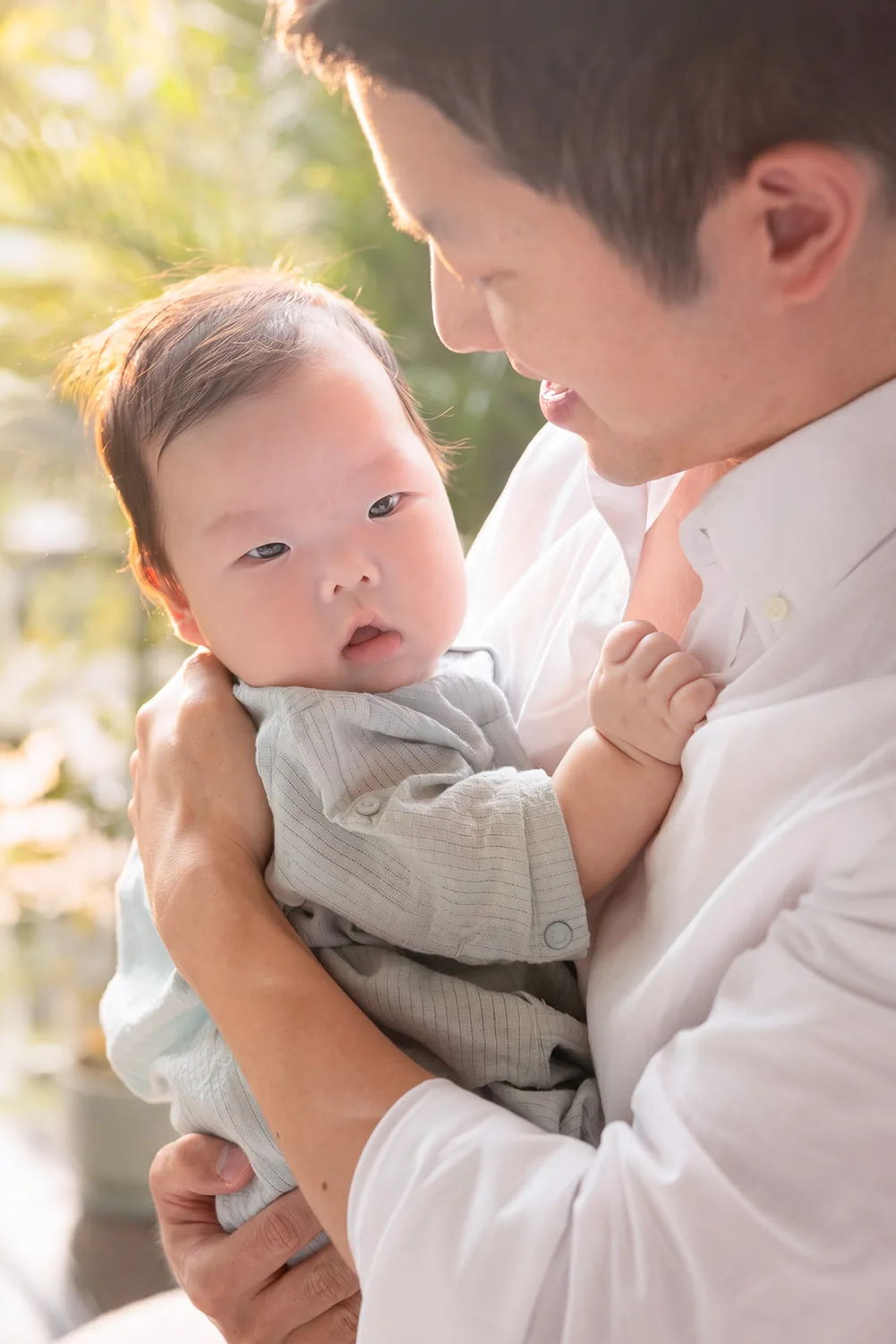 Ji holding Juwon by the window during a Korean 100-day family photoshoot in Singapore