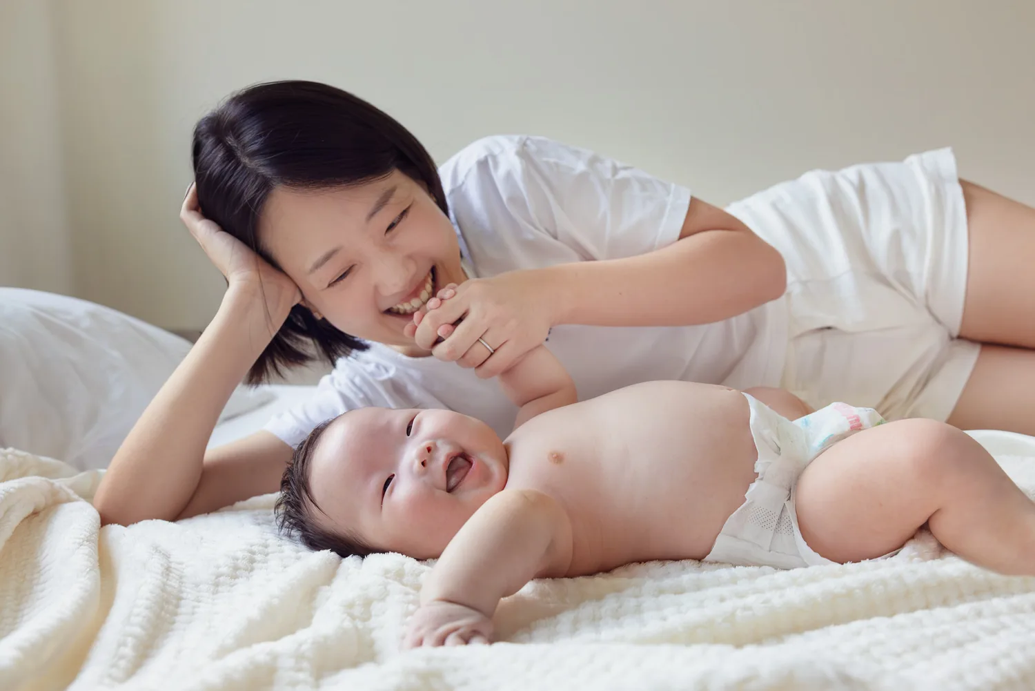 Kristin lying beside Juwon during a quiet at-home baby session in Singapore
