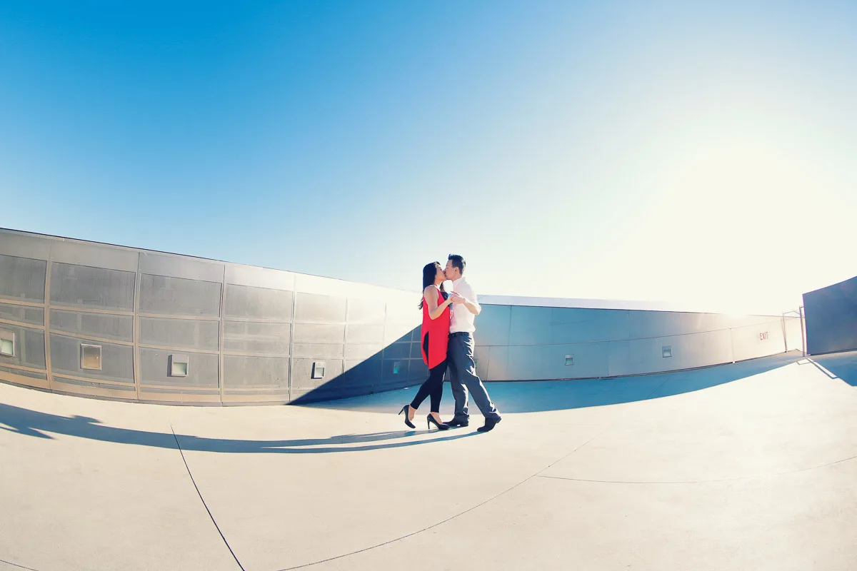Julie and James standing small against modern Los Angeles architecture during their engagement session