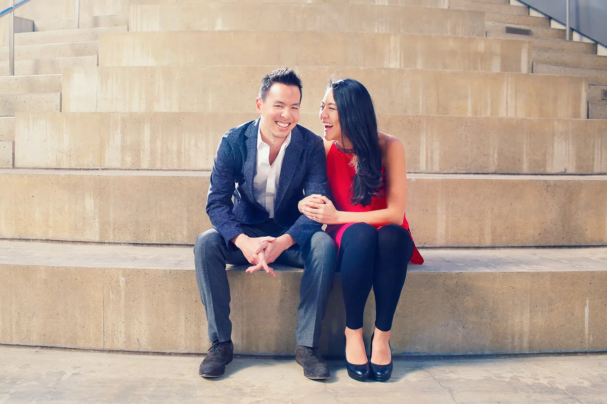 Julie and James laughing together on concrete steps during their Los Angeles engagement session