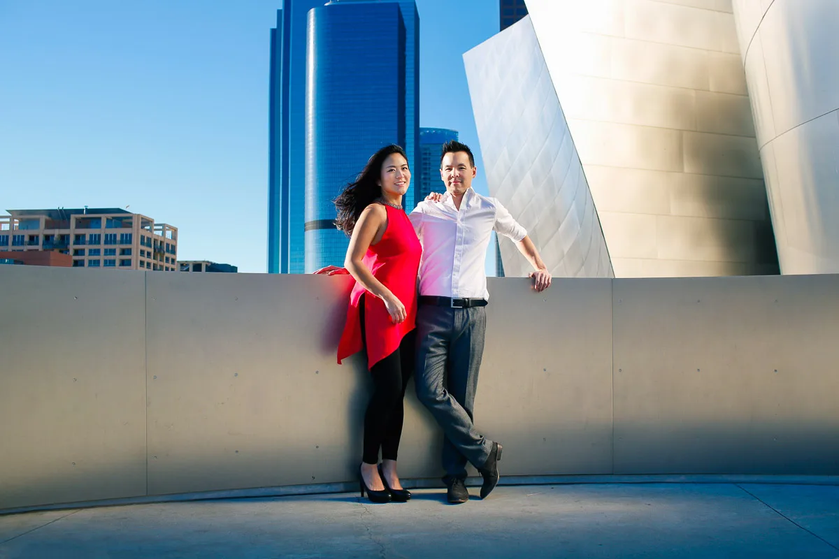 Julie and James laughing together beside reflective architecture in Los Angeles