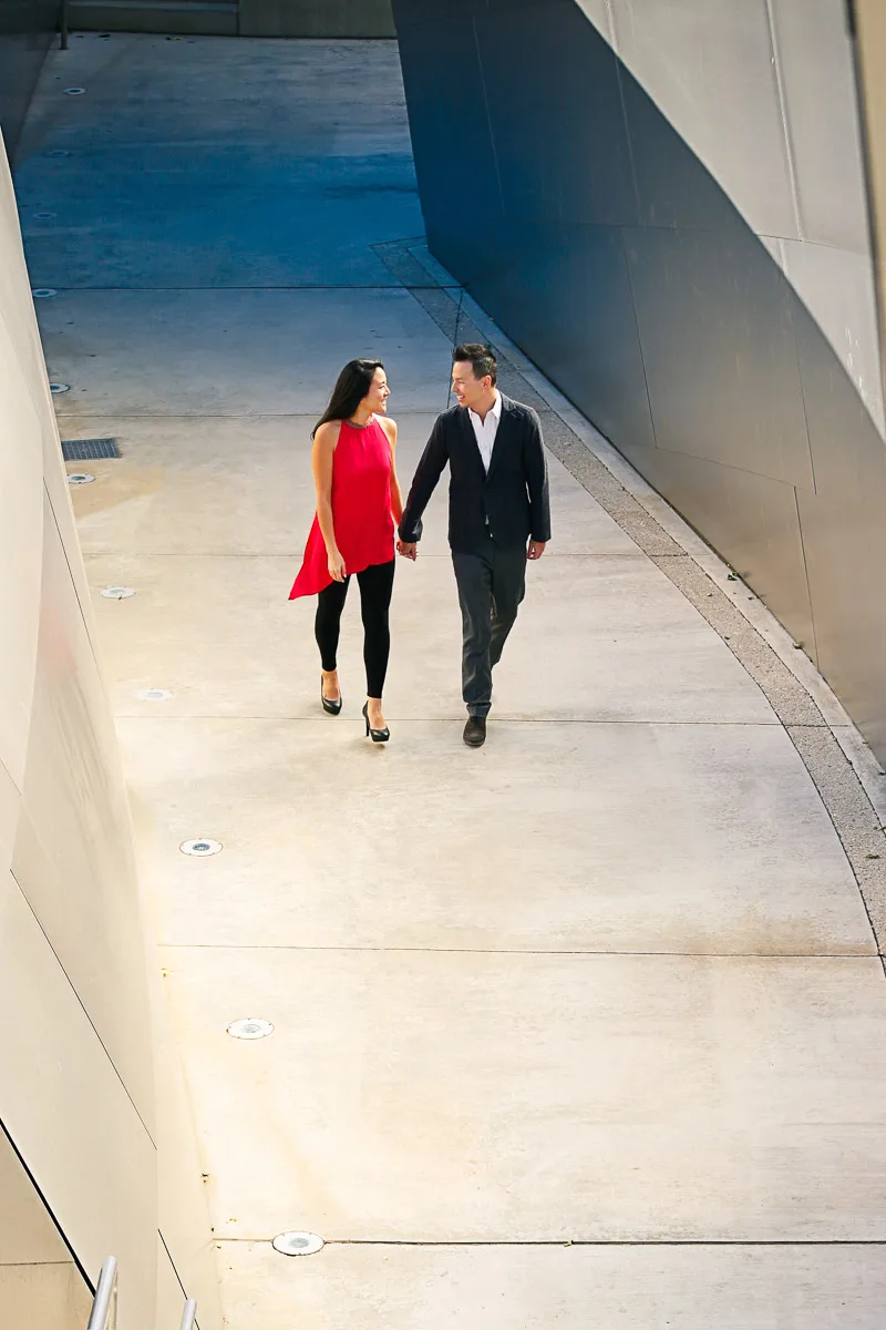 Julie and James walking through a narrow architectural corridor during their Los Angeles engagement shoot
