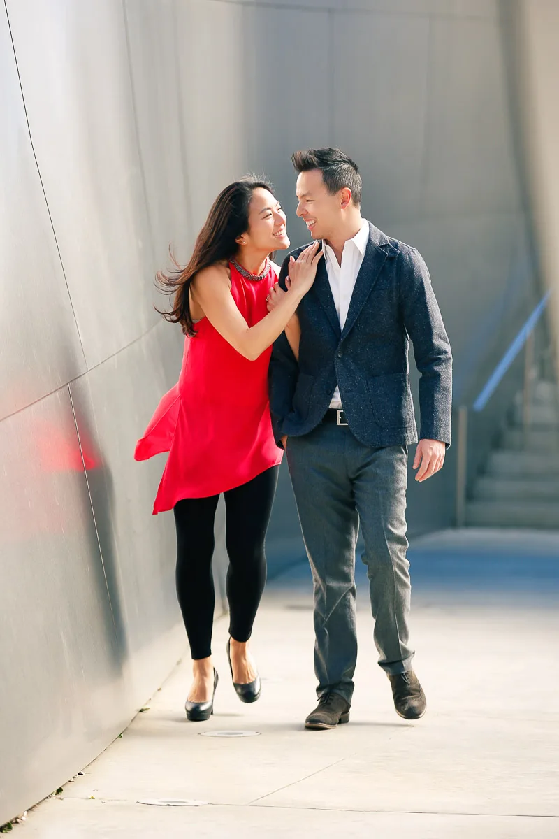 Julie and James walking together through sunlit modern architecture in Los Angeles