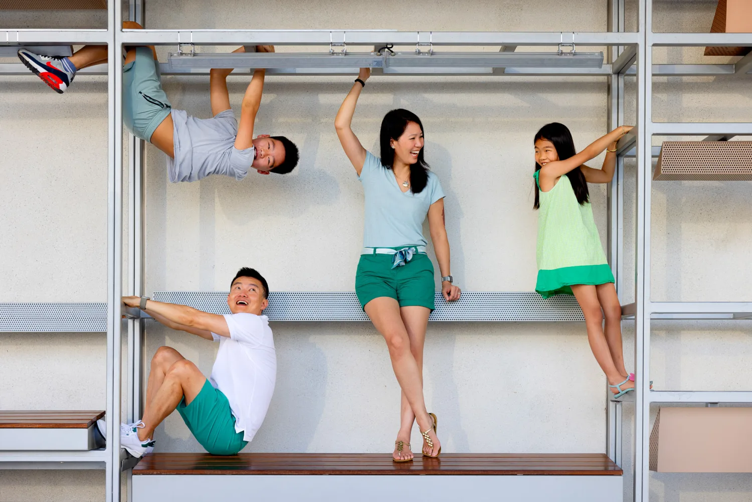 The whole family playfully climbing and hanging from a structure near Marina Bay