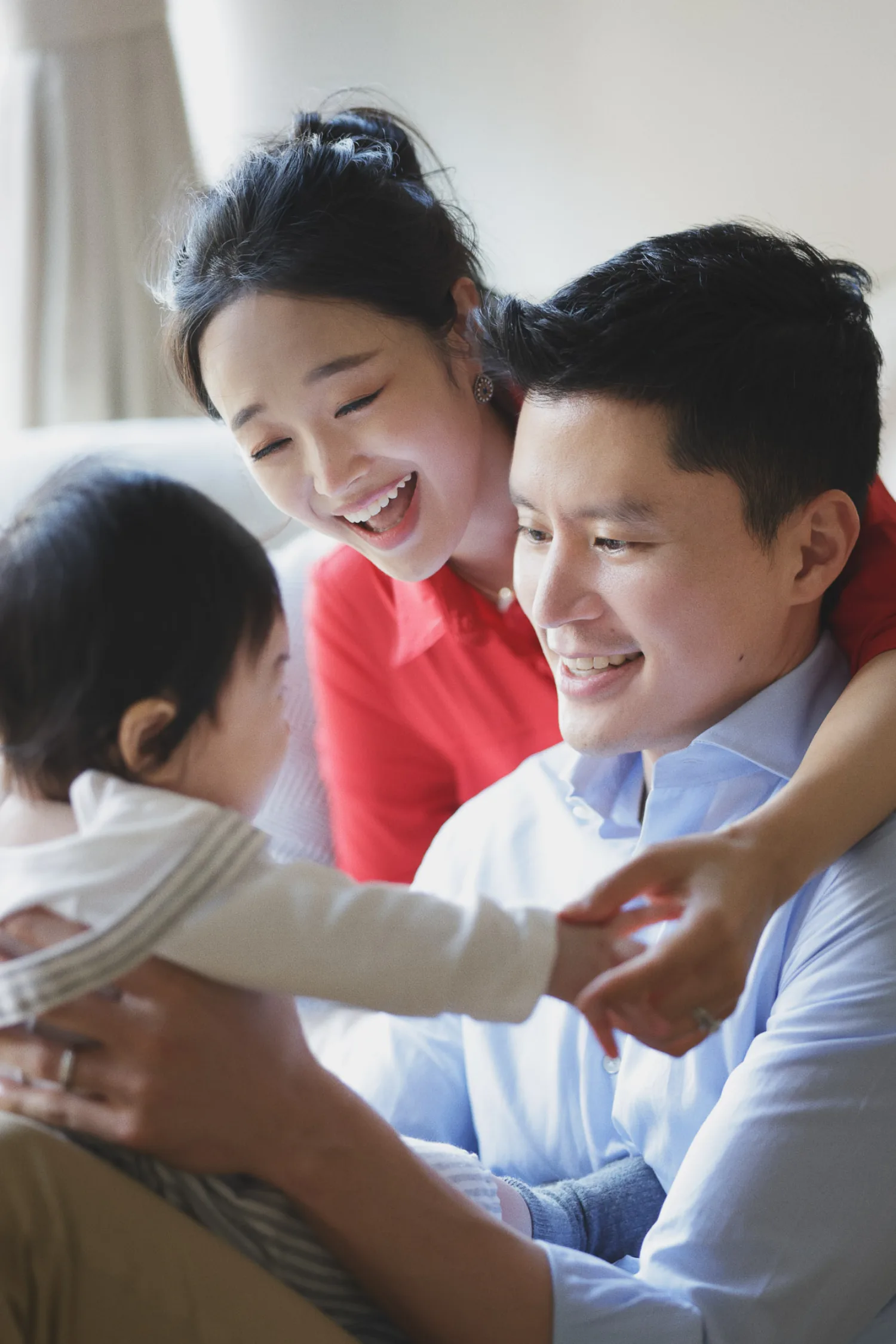 Joyful family portrait with parents and newborn baby during indoor shoot in Singapore