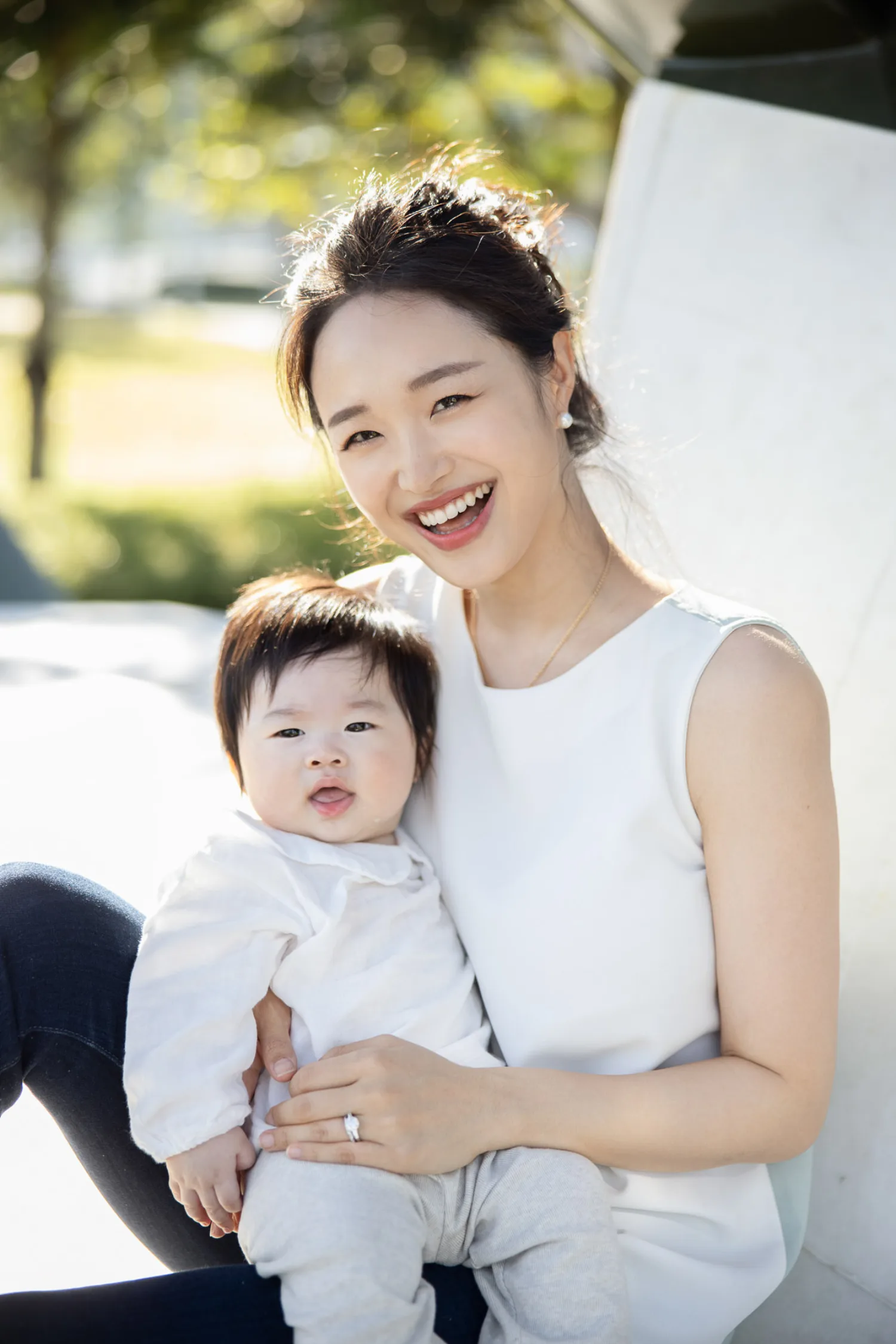 Beaming mother with her adorable newborn in natural outdoor light
