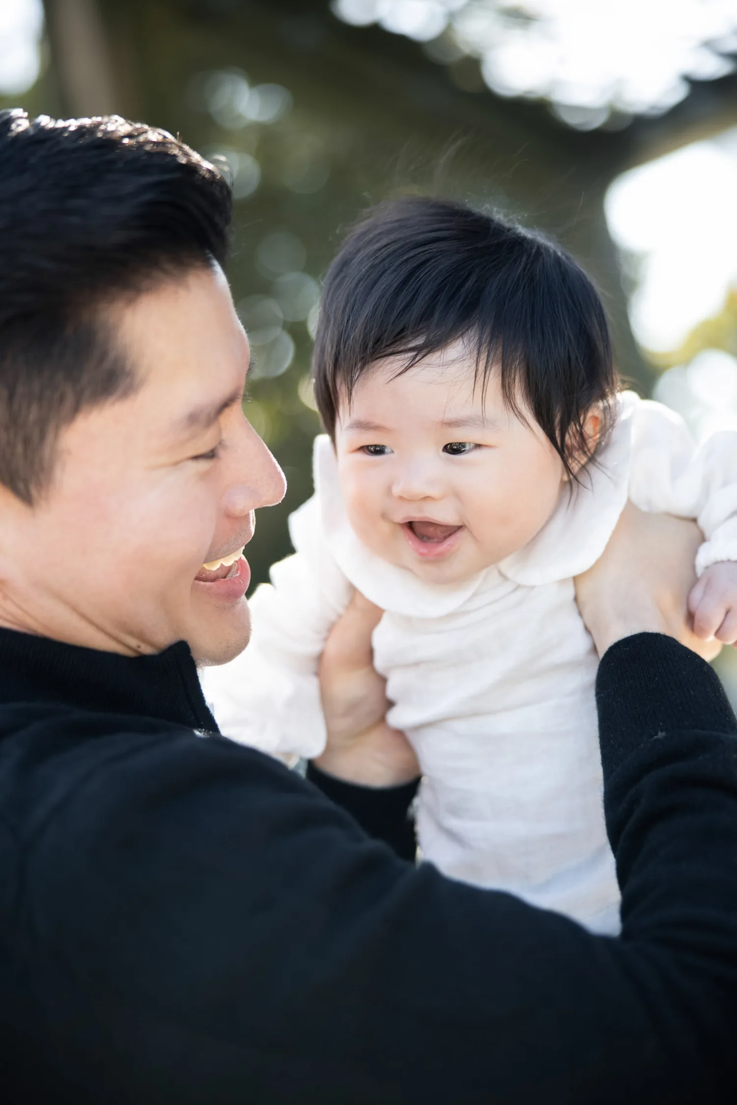 Father joyfully lifting his newborn baby during outdoor family session