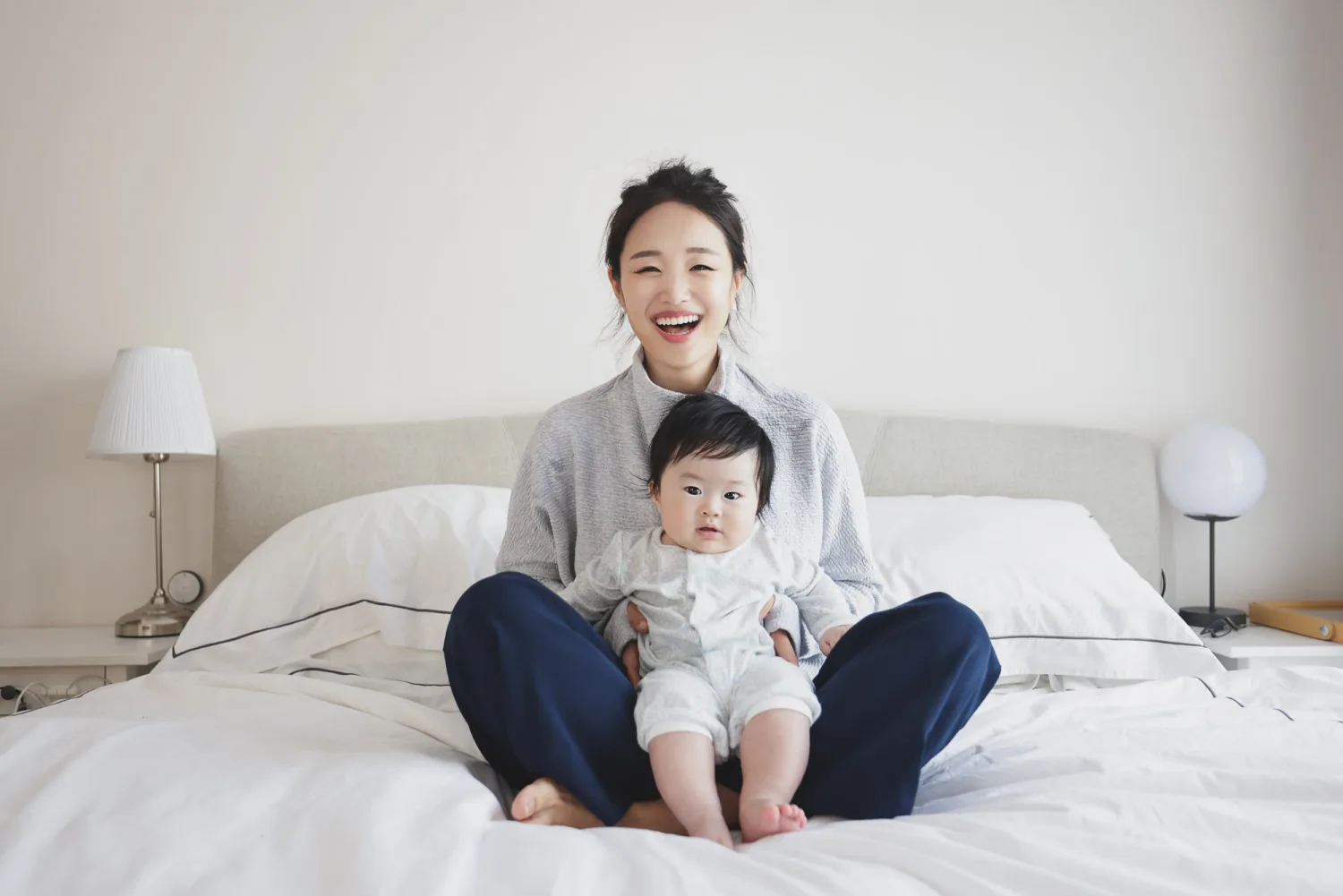 Mother beaming with joy while holding her newborn baby at home in Singapore