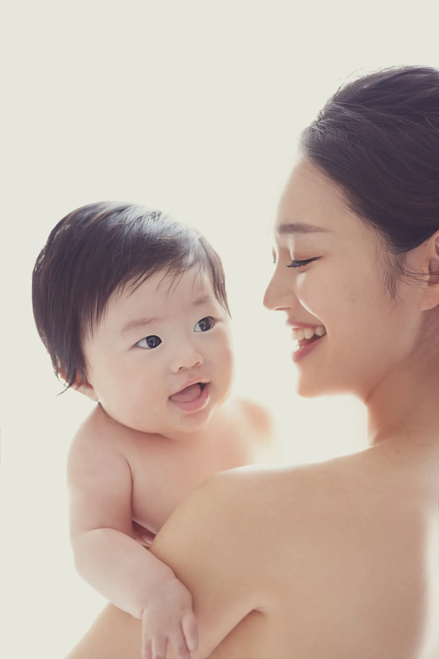 Radiant mother joyfully holding her baby during portrait session