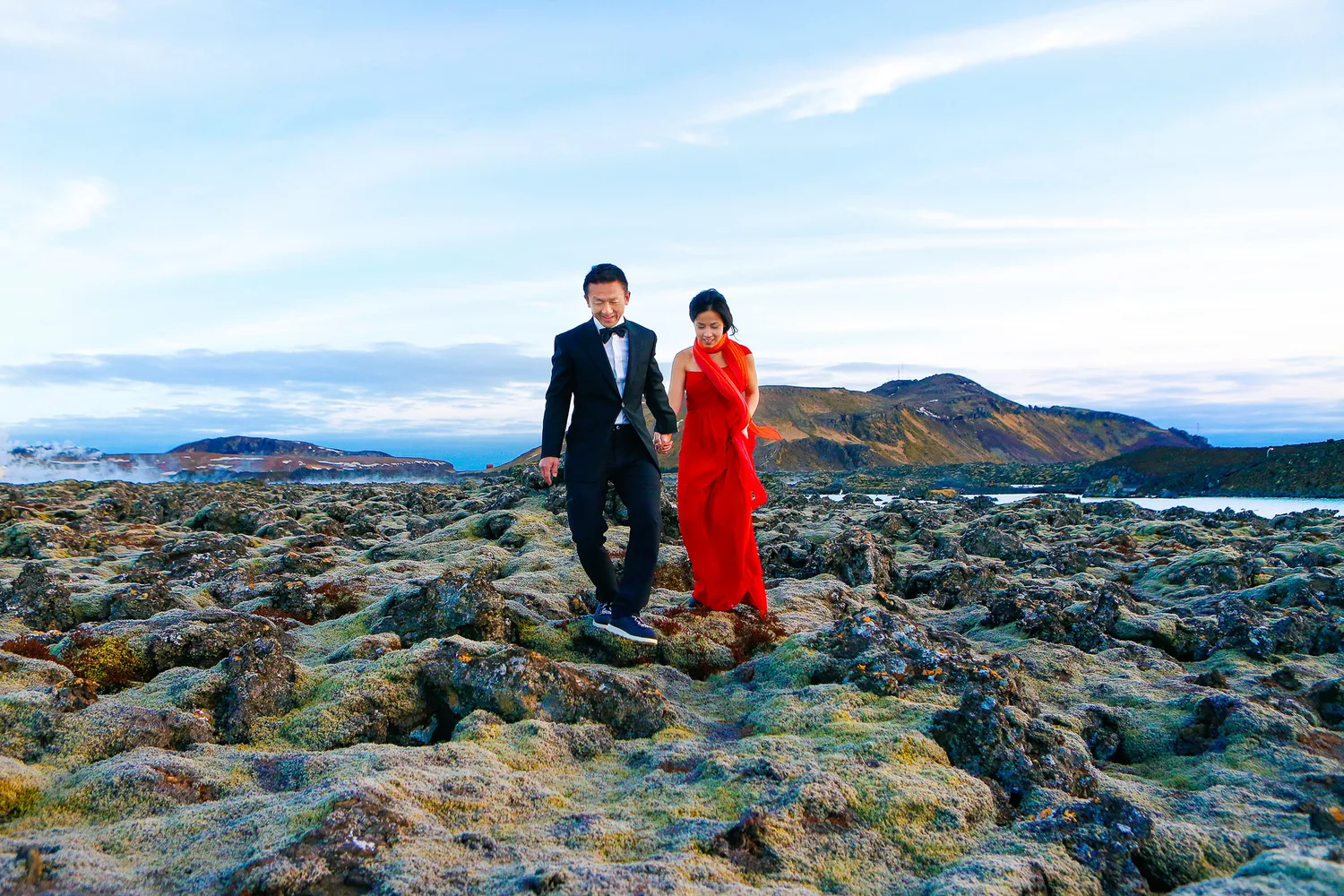 Desiree and Derek walking through moss-covered lava fields in Iceland during their engagement session