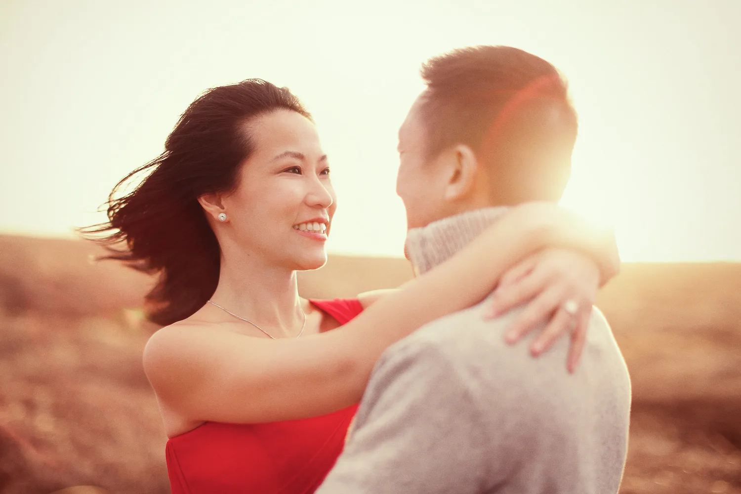 Desiree and Derek embracing in a windswept Iceland field at golden hour