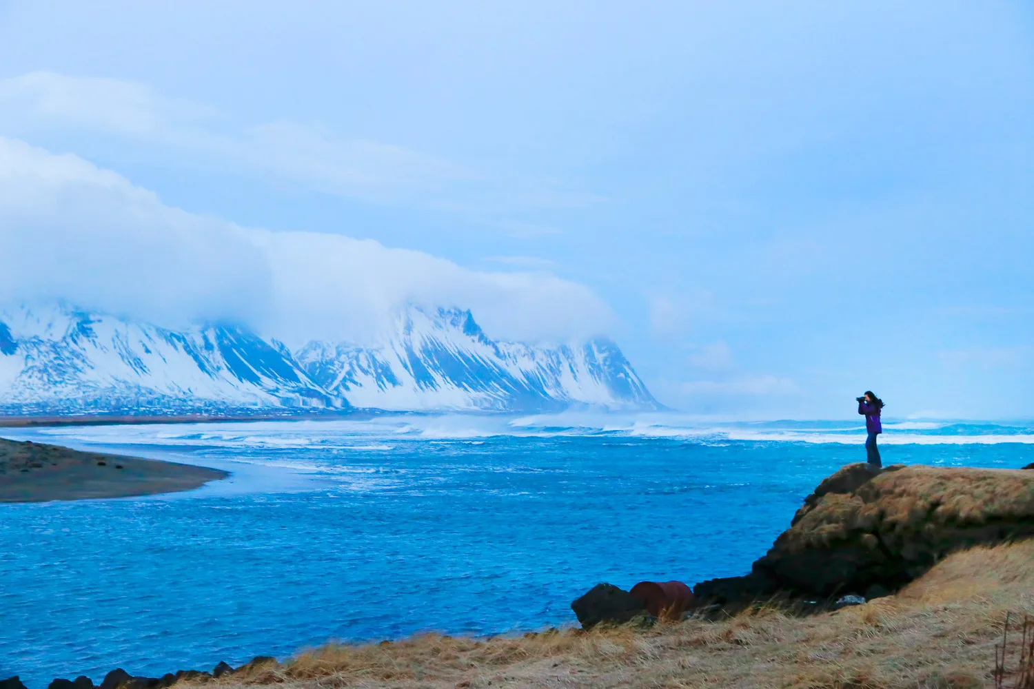 A lone bundled figure looking out across Iceland's cold open landscape