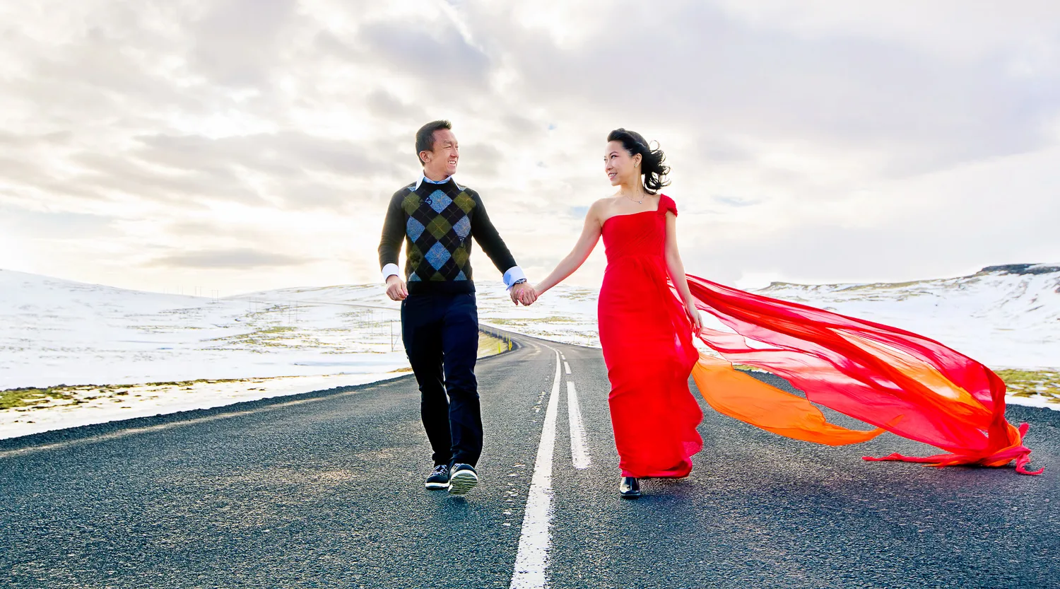 Desiree and Derek walking hand in hand down a snowy Iceland road