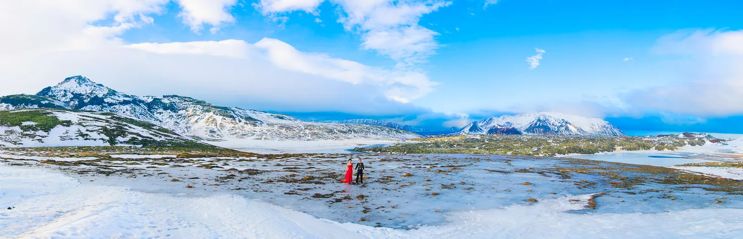 Wide view of Desiree and Derek in a vast snowy Iceland landscape