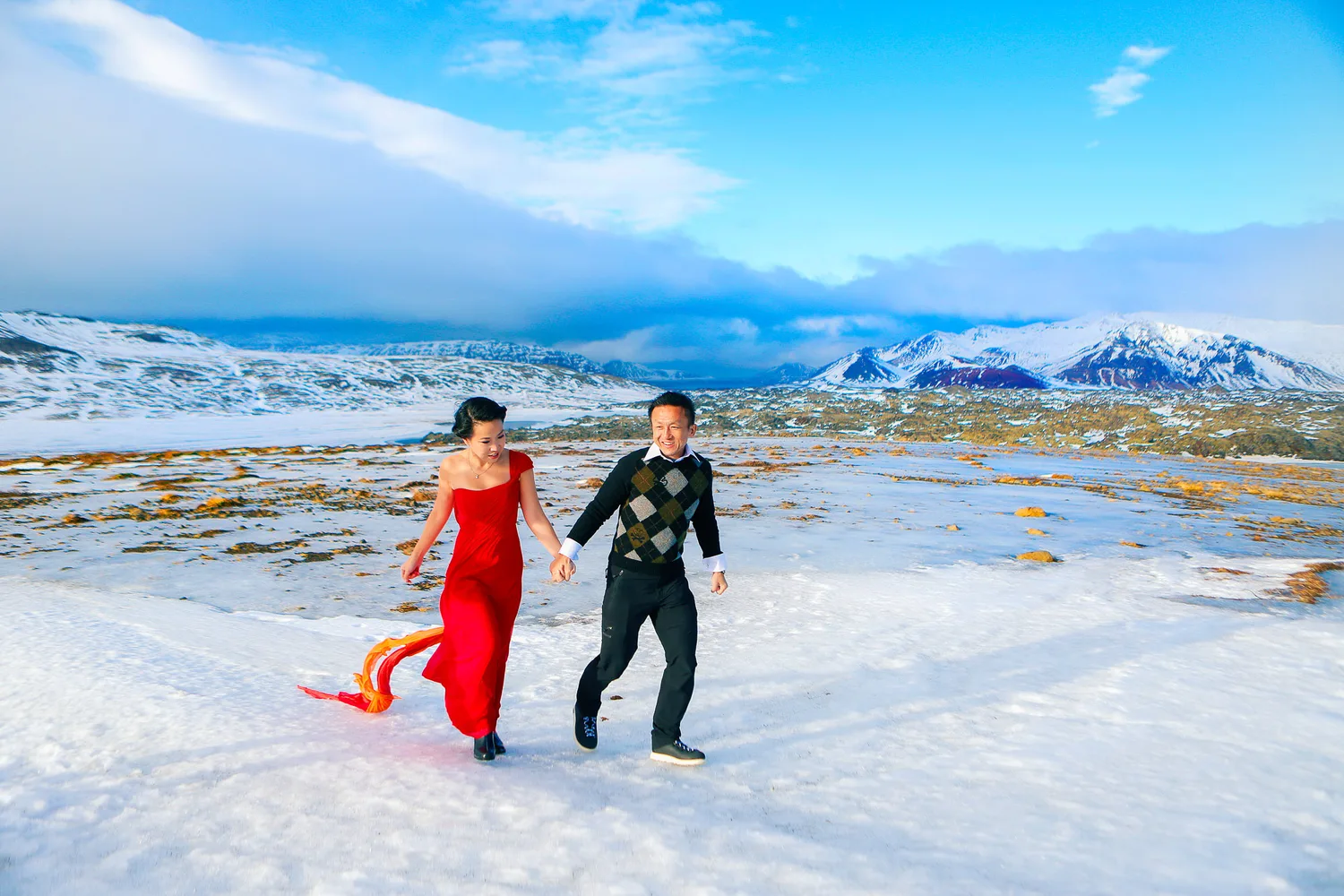 Desiree and Derek running together across snow in Iceland during their engagement shoot