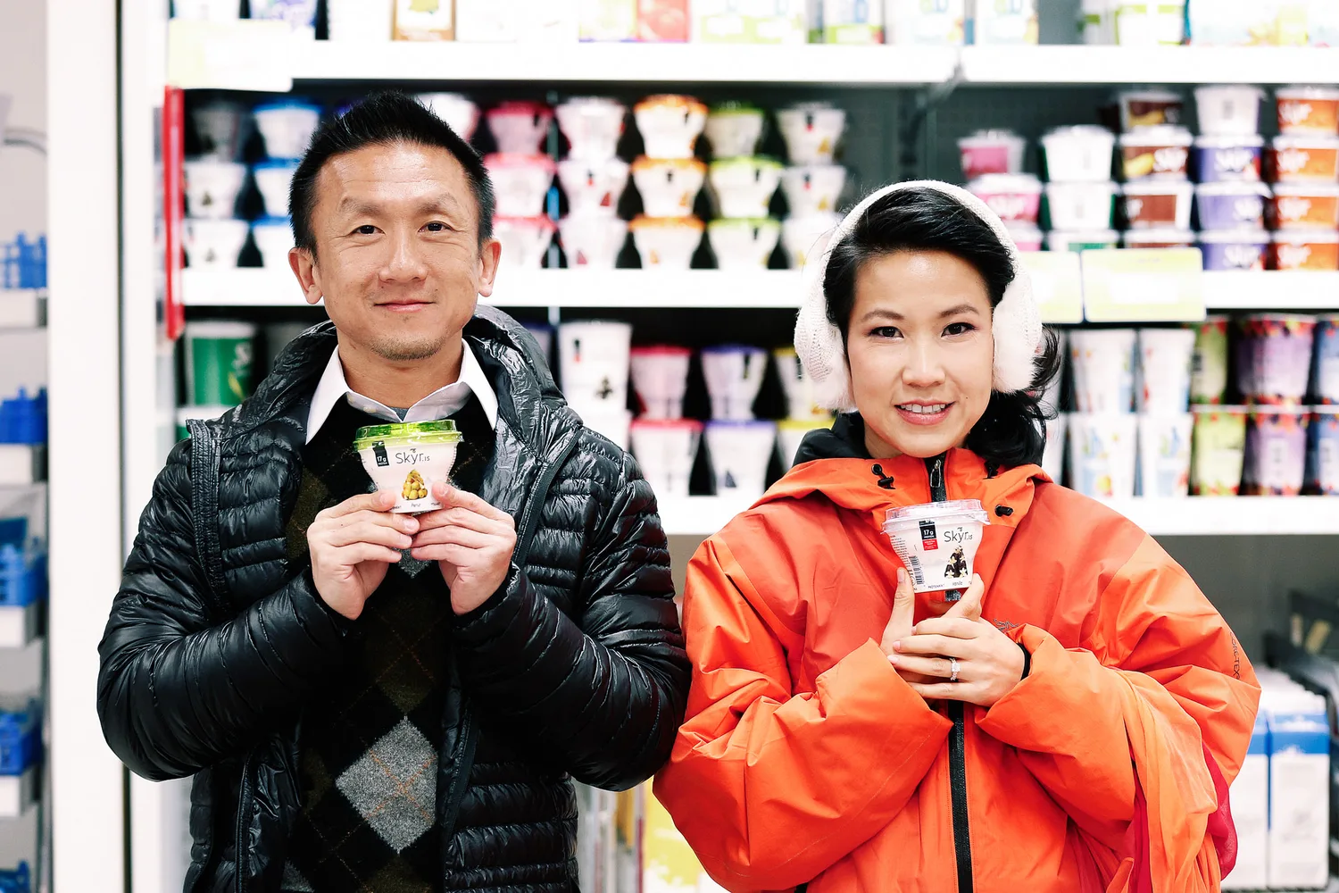 Desiree and Derek in winter jackets holding skyr inside an Iceland supermarket