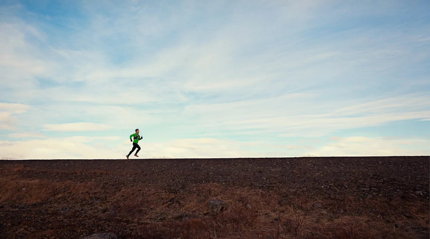 A runner moving across Iceland's empty landscape during Desiree and Derek's engagement trip