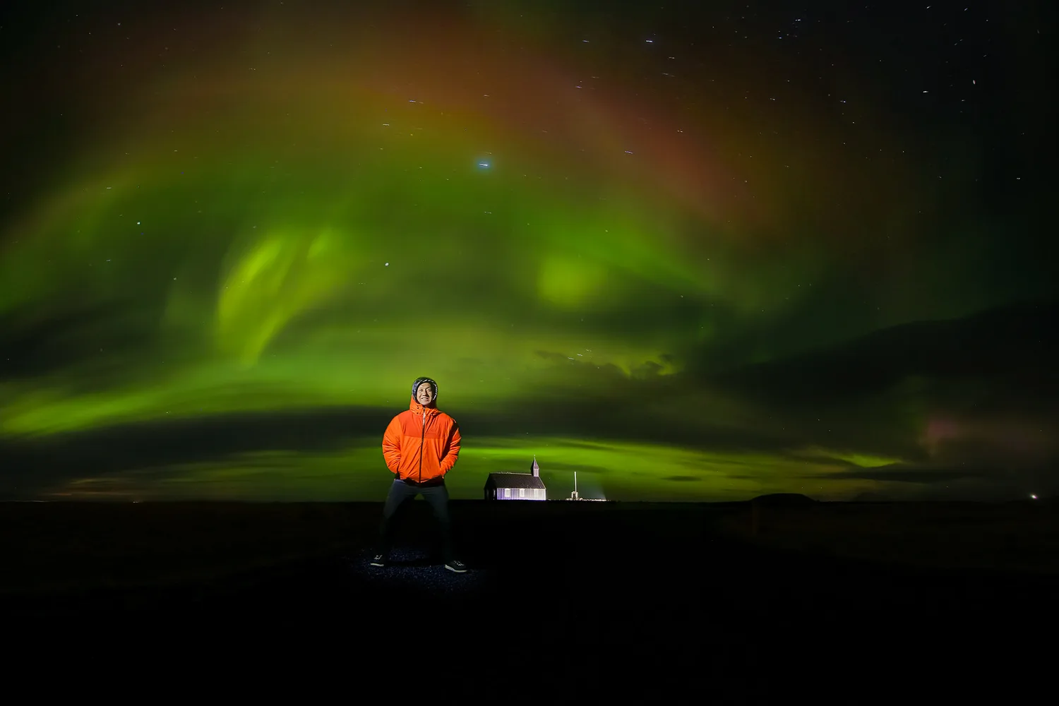Derek standing outside their future Iceland church beneath the northern lights