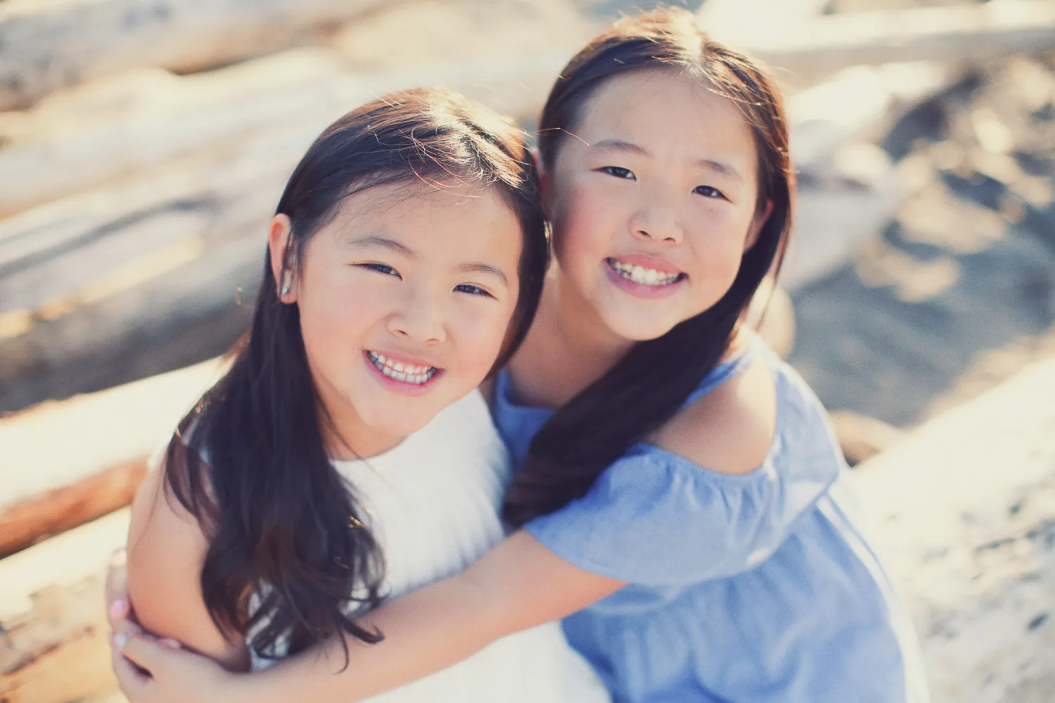 Two sisters hugging and smiling during a Vancouver beach family session