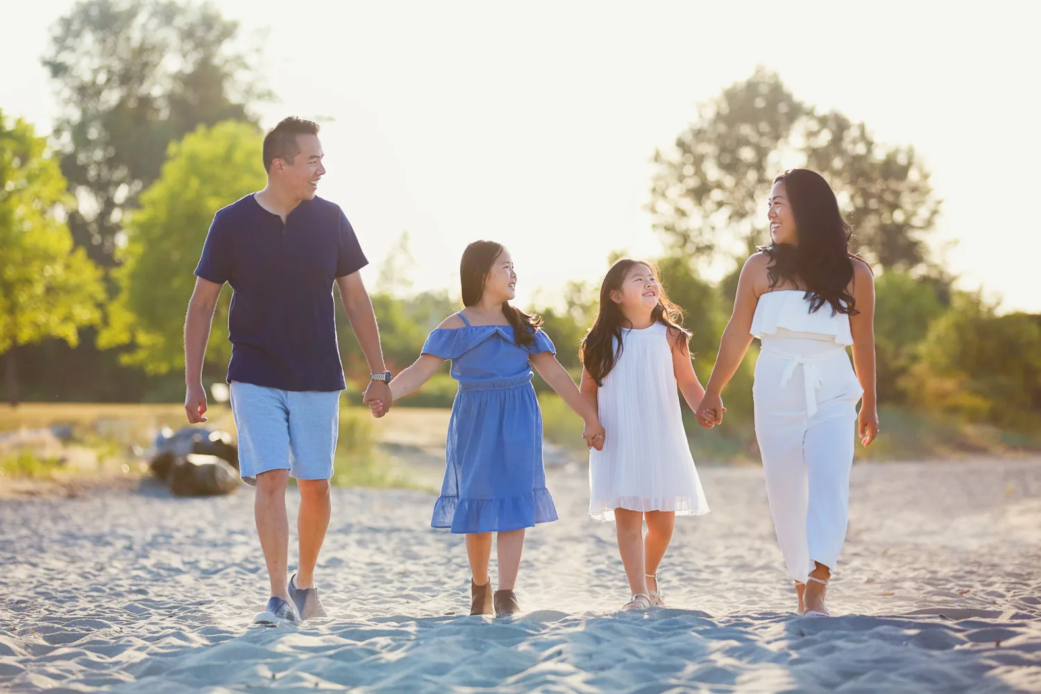 Jen, Evan, and their two daughters walking together on the beach in Vancouver