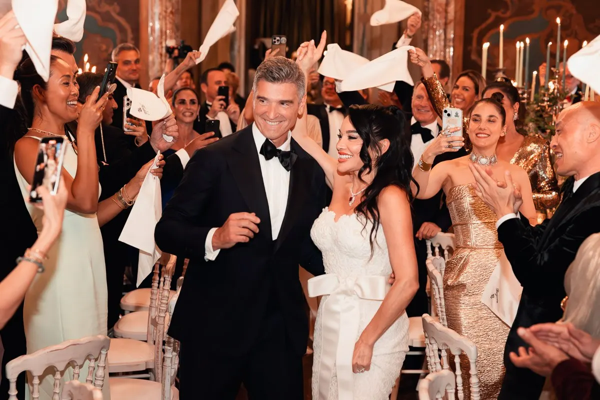 Vera and Emilio surrounded by cheering guests waving napkins in the candlelit reception hall
