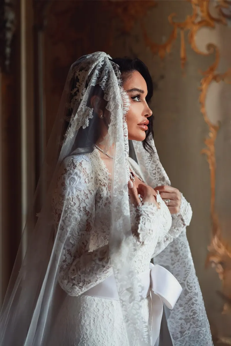 A close-up bridal portrait of Vera in profile, her lace veil and gown against the villa's ornate gold detailing