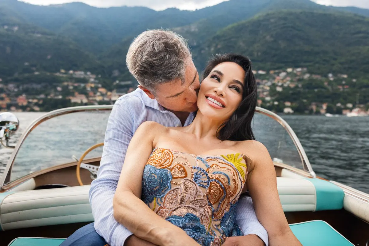 Vera and Emilio sharing a kiss on a Lucia boat the day before the wedding, the hills of Lake Como behind them