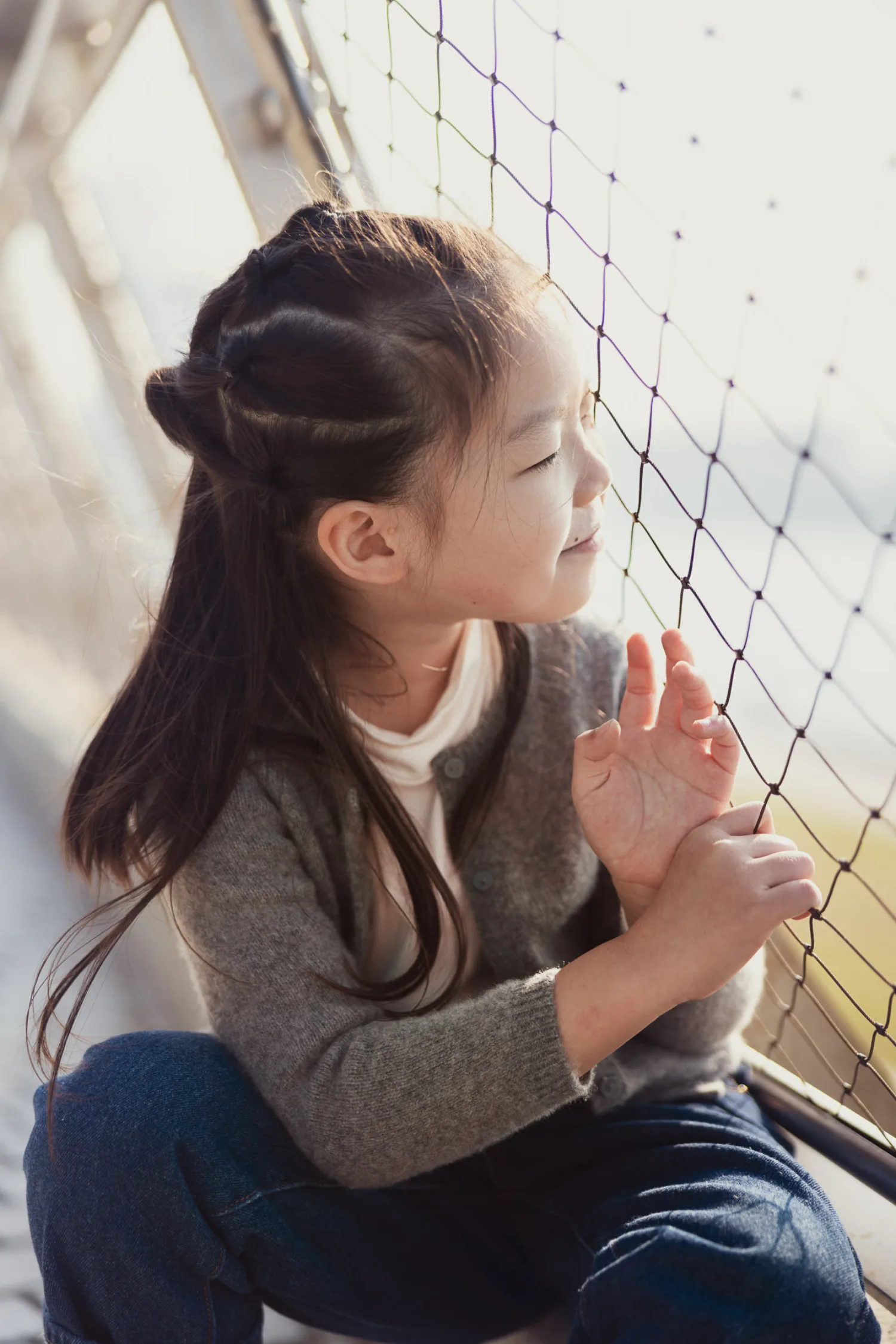 Emma looking thoughtfully through a mesh fence at West Kowloon, a quiet moment between all the running