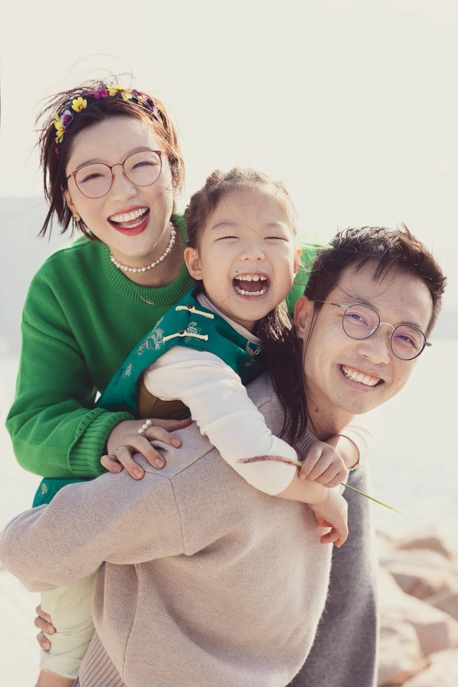 The whole family laughing together at West Kowloon — Emma on Vincent's back, Bonnie's arms around them both, pure joy
