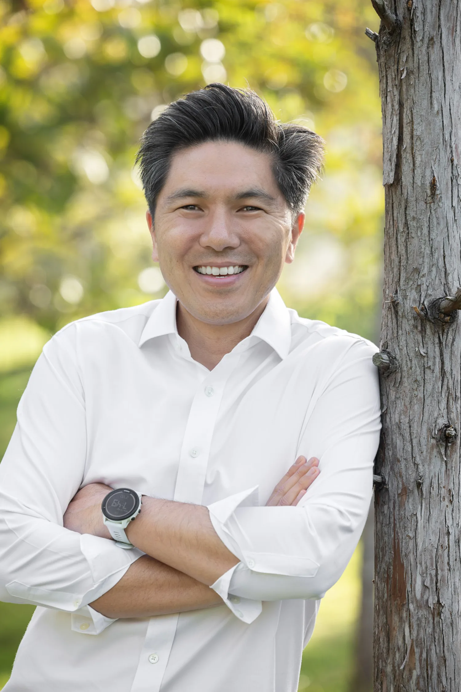 Terence leaning against a tree with a relaxed smile, sunlight filtering through the foliage