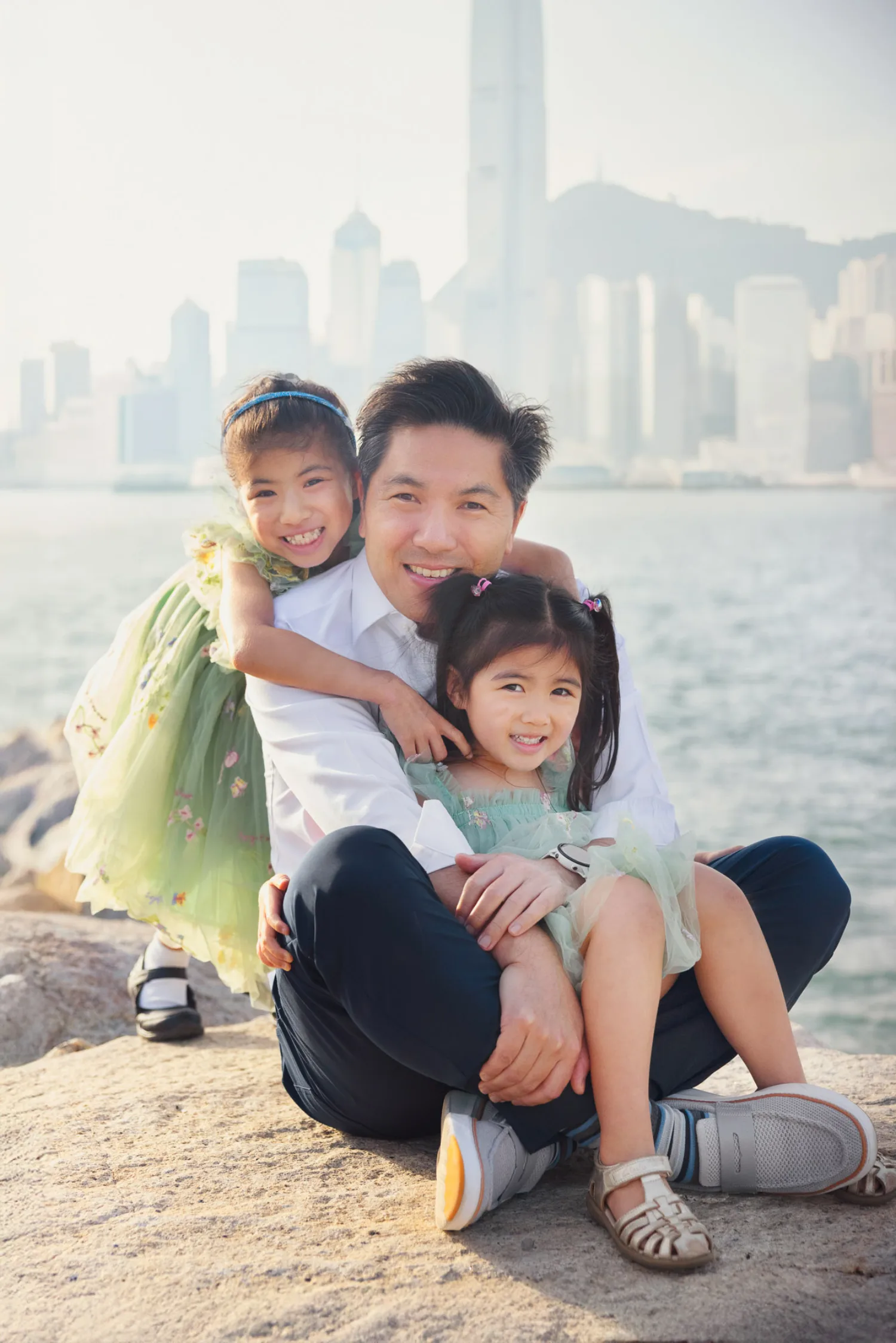 Terence with Sophie and Zoe on his lap, Hong Kong skyline across the harbour