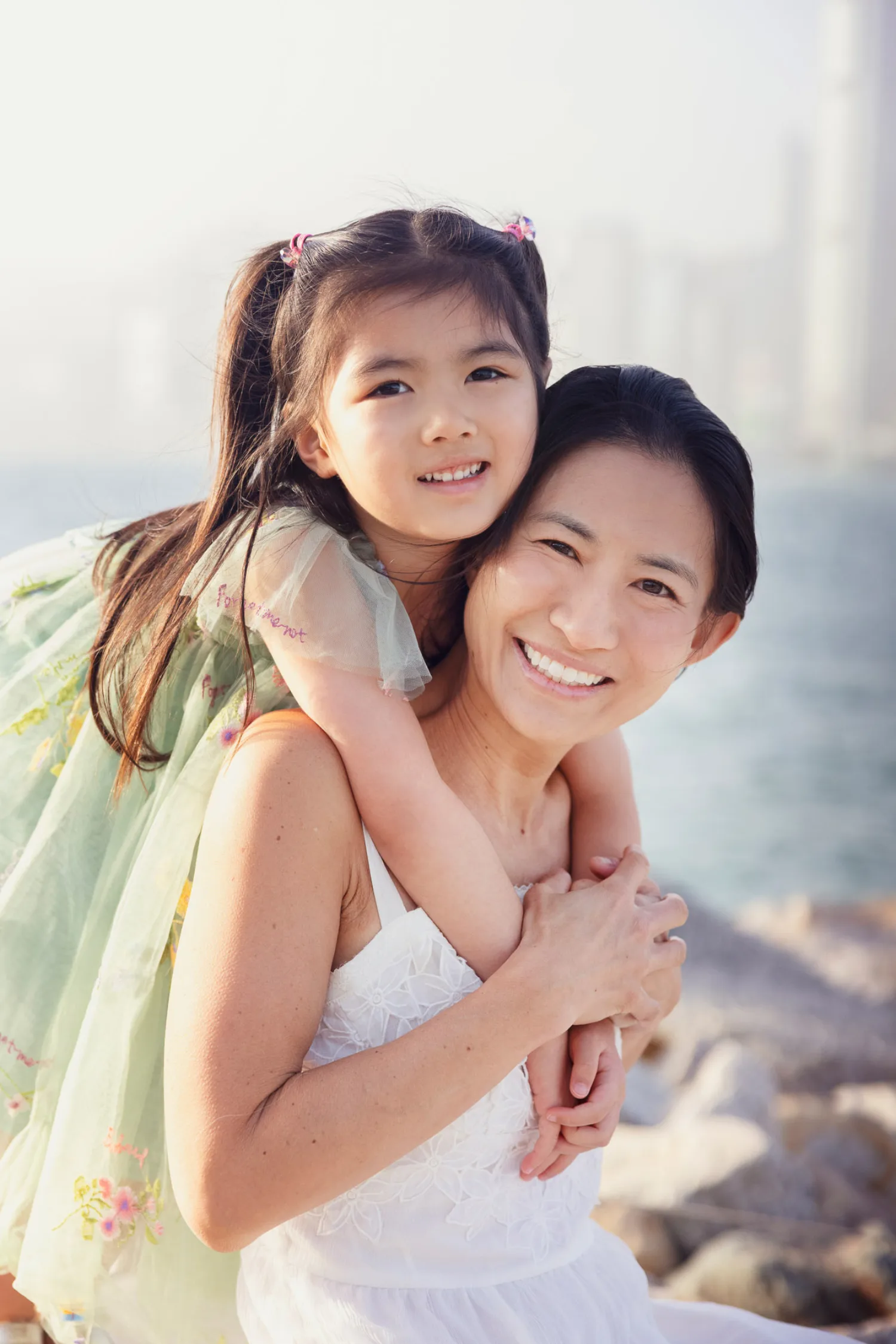 Suzanna and Zoe share a joyful piggyback moment on the waterfront rocks
